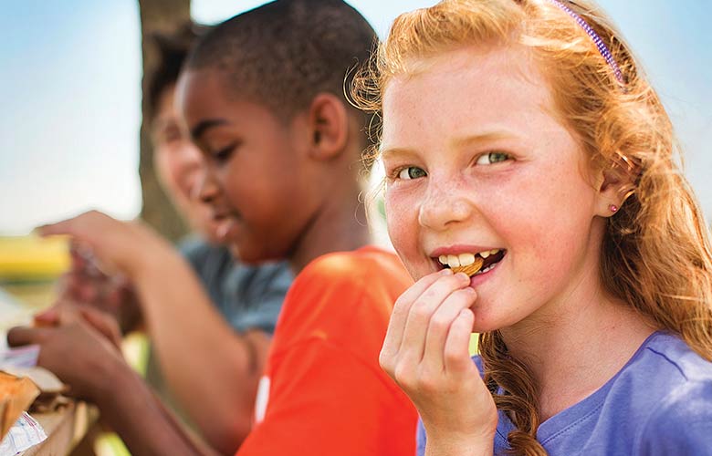 Group of school student sit together eating lunch