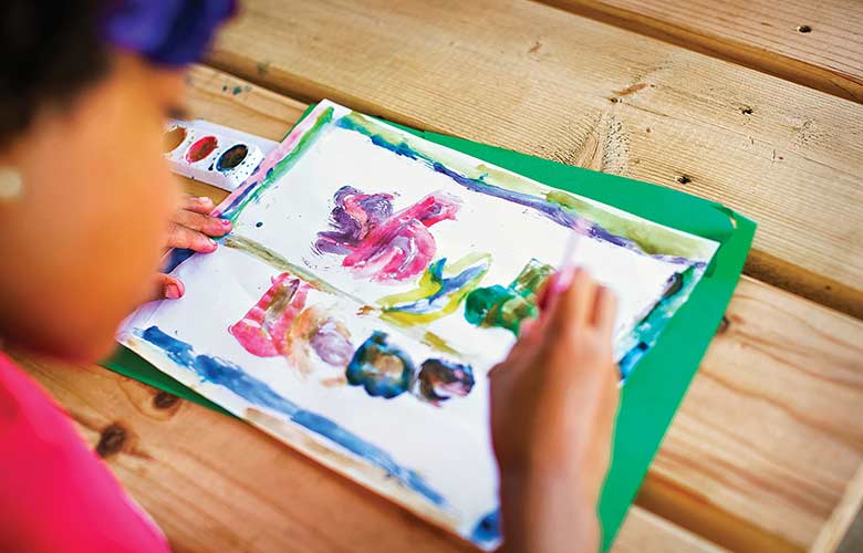 Child paints a picture at her desk