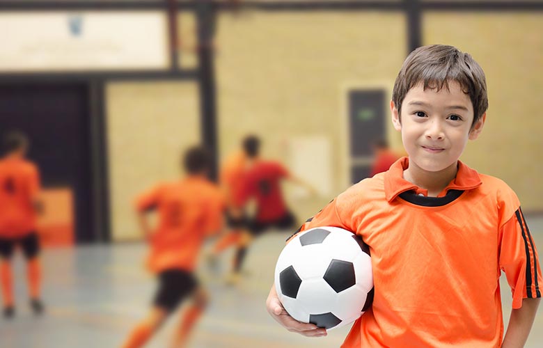 Young boy holding soccer ball inside
