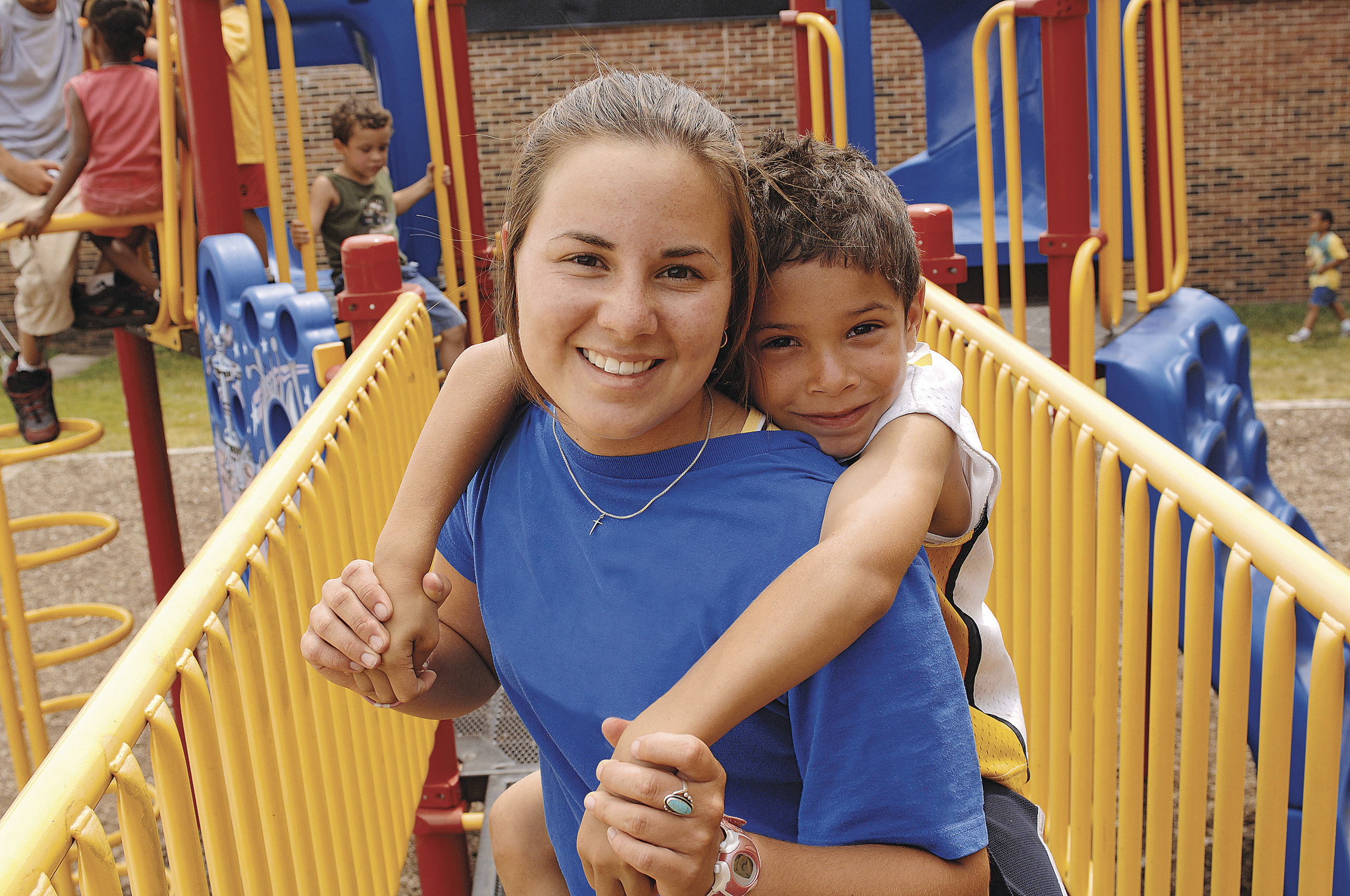 Child piggybacks on volunteer on playground