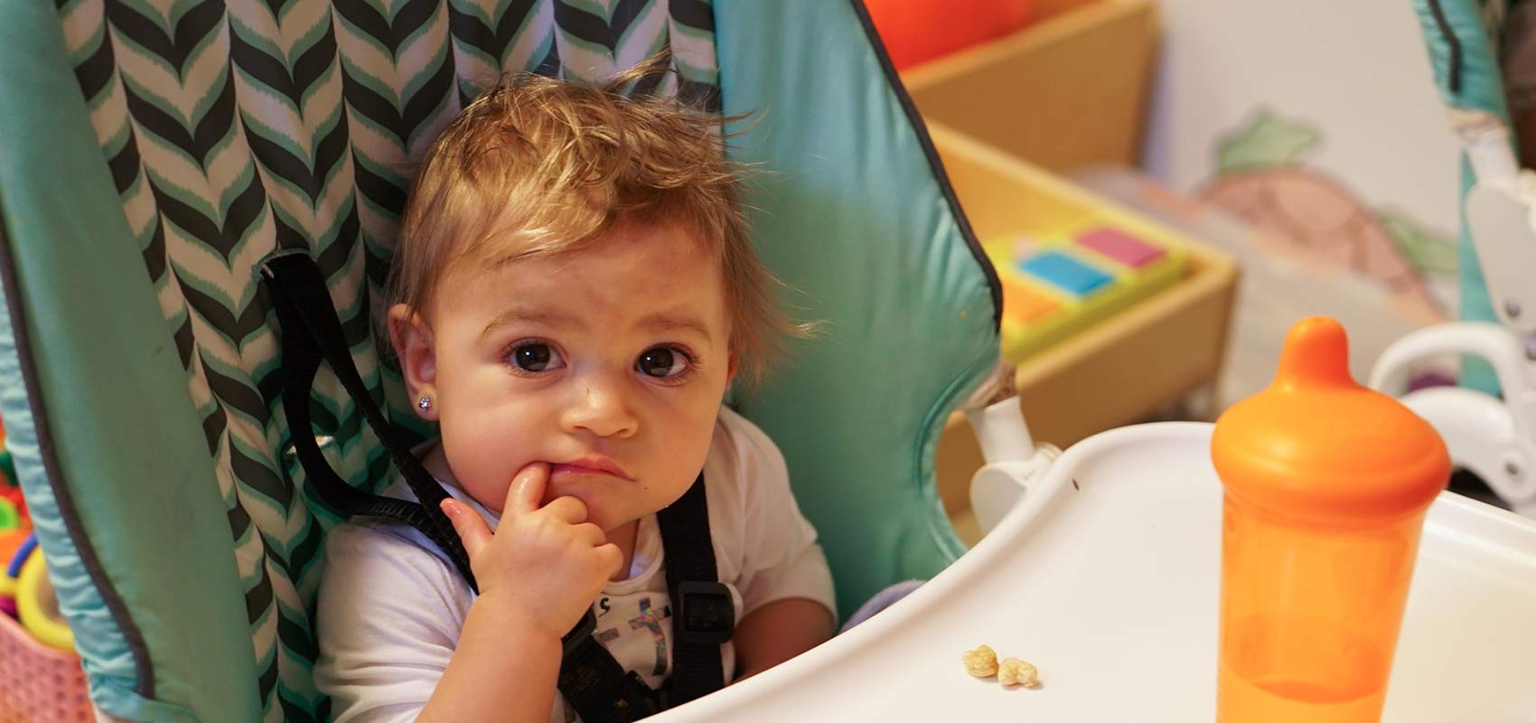 Baby eats snacks in highchair in classroom