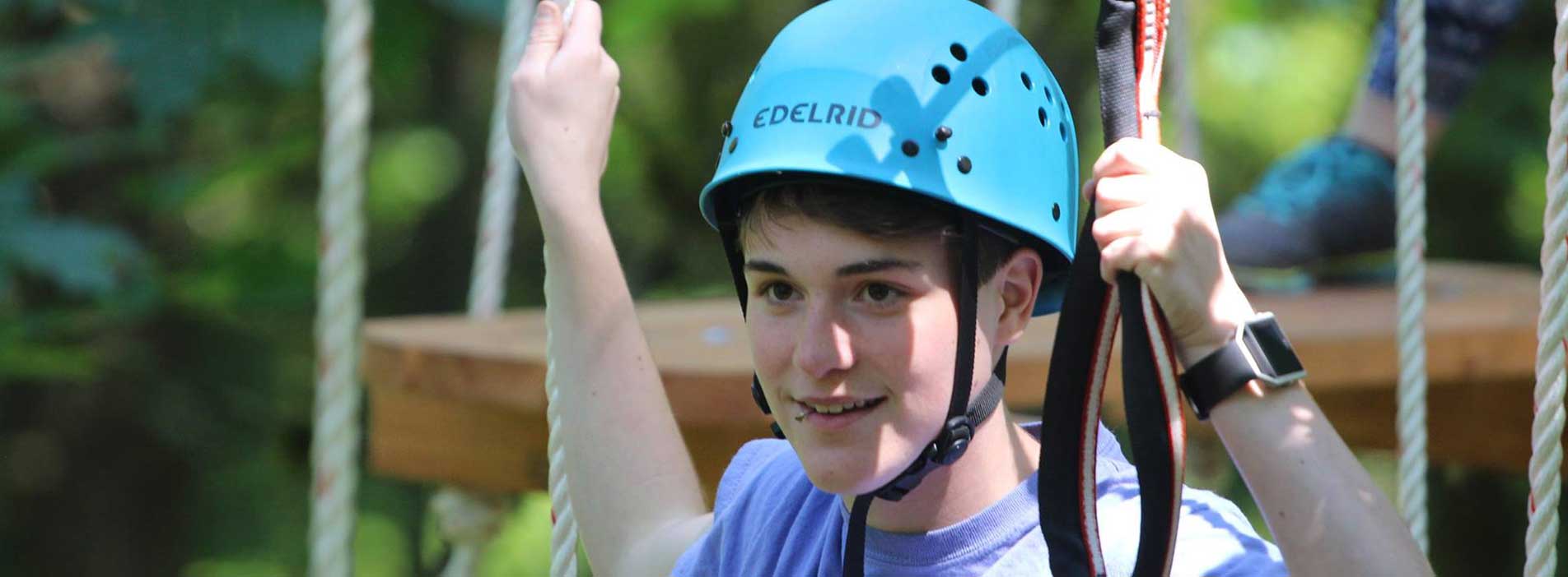 Boy wearing helmet on rope obstacle course
