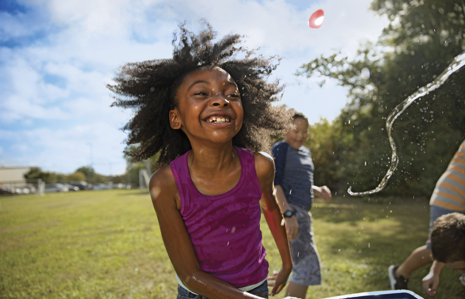 Children play with water balloons on sunny day