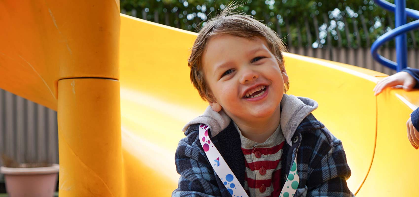 Young boy smiles as he sits on slide at playground