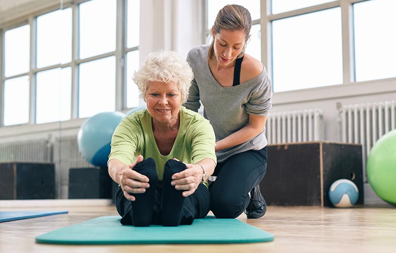 Older woman stretching with a personal trainer