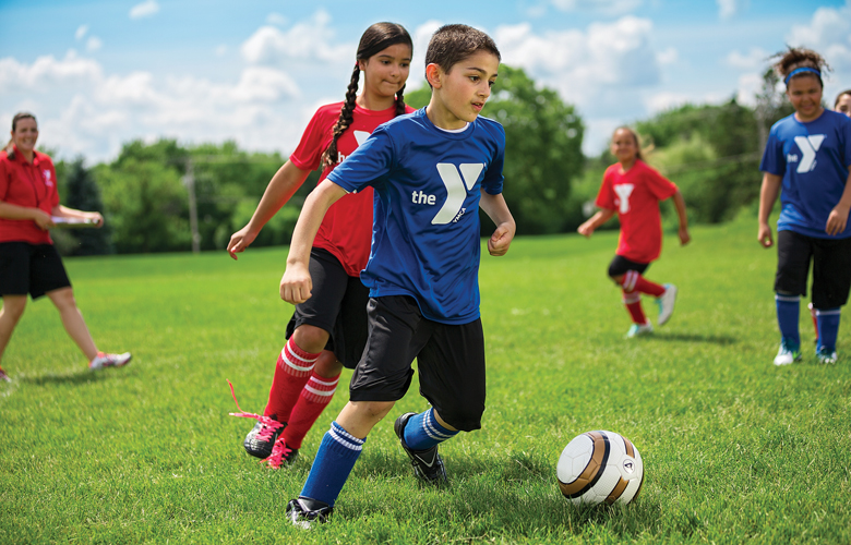 Young boys and girls playing soccer outdoors