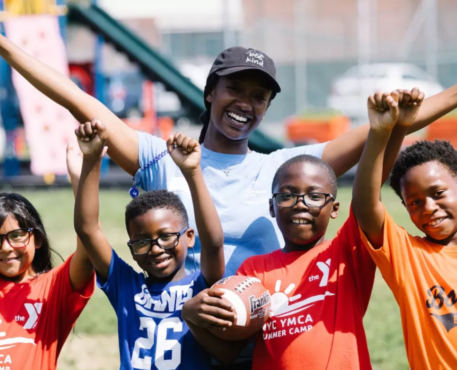 A group of young children pose for the camera with a football
